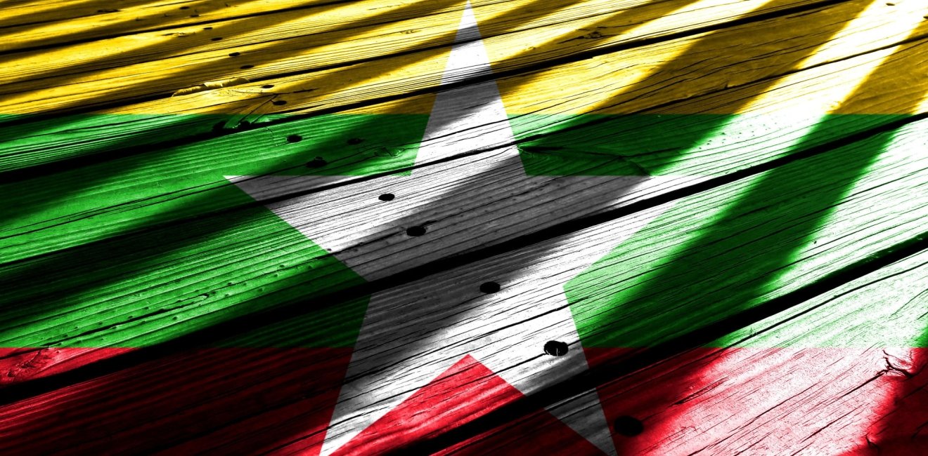 The flag of Myanmar with bars of light shining on it.