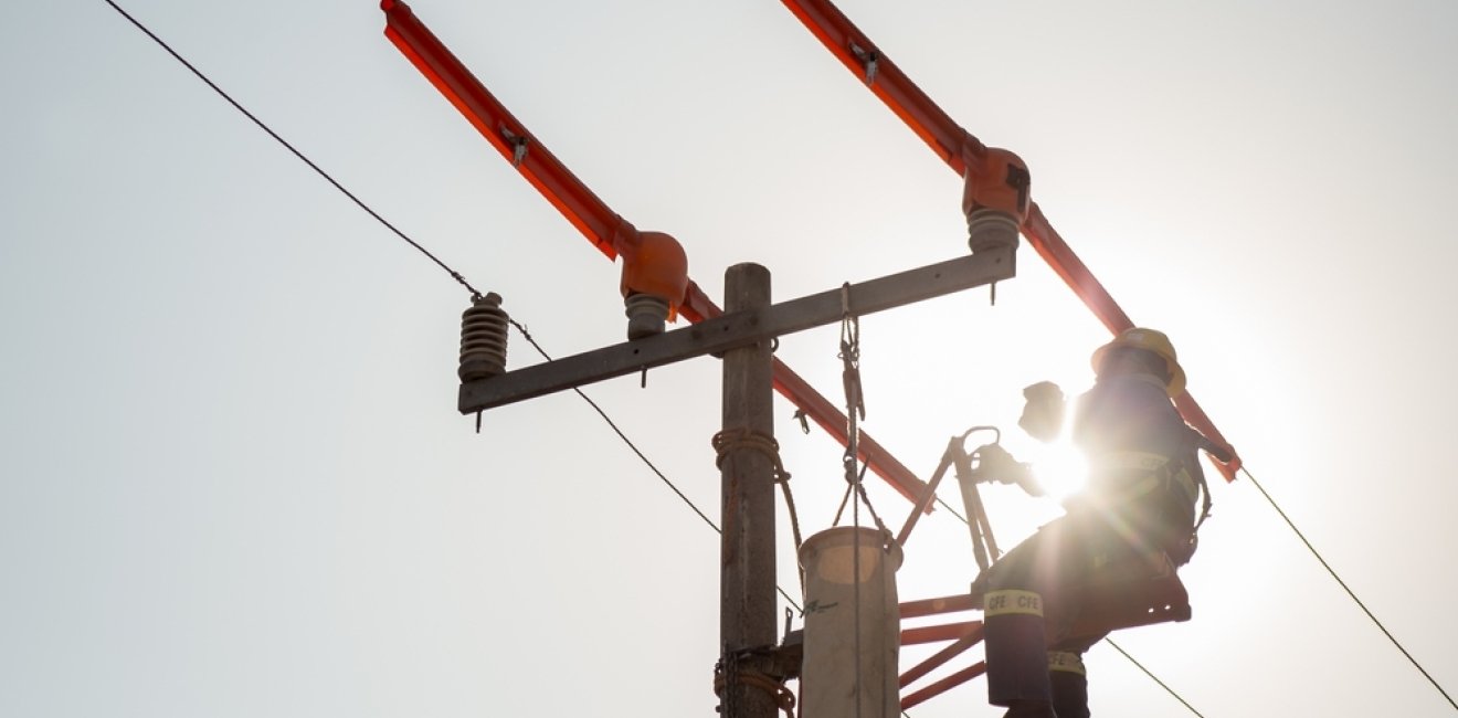 Lineman electrician engineer working climbing a pole to repair and maintain a power line and a transformer