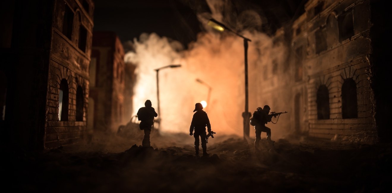 Army sniper with large caliber rifle standing in the fire and smoke