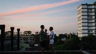 Husband, wife, and baby on balcony overlooking city