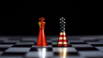 Chess pieces stand text to each other wrapped in the US and Chinese flags