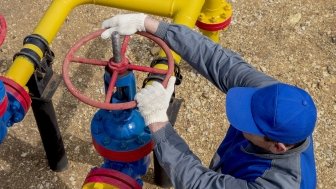 Image of a worker opening, closing the shut-off valves at the gas pumping station. Part of the photo is blurry.