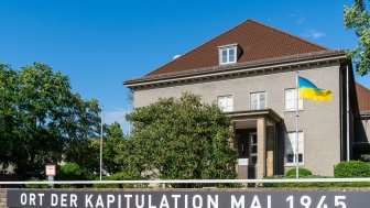 The Berlin-Karlshorst Museum with sign stating "Place of Surrender May 1945" and flying the flag of Ukraine