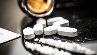 A detailed view of fentanyl pills and white powder on a reflective surface, illustrating the opioid crisis and prescription drug misuse. Subtle reflections and contemporary elements enhance the scene.