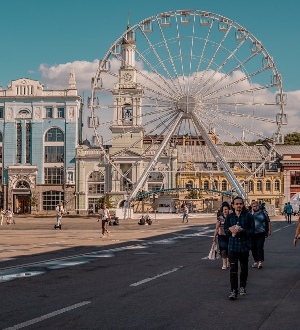 Podil, Kyiv, Ukraine - June 16, 2021 - street shot of people on the main square of the Podil neighborhood with ferris wheel and traditional architecture