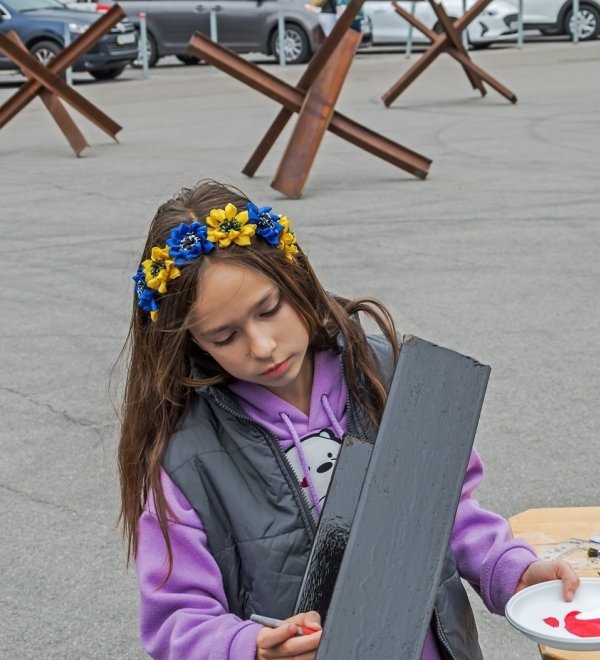 Young person painting wearing flower crown with Ukrainian National Colors