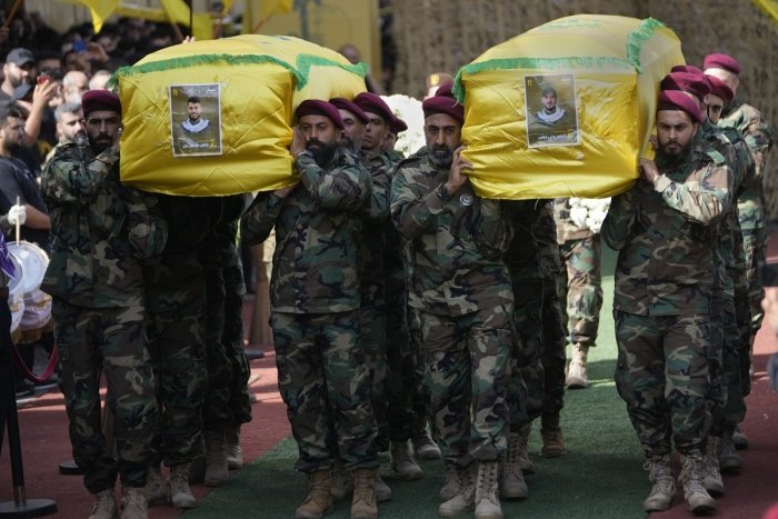 Hezbollah members carry the coffins of two of their comrades during a funeral procession in the southern suburbs of Beirut, Thursday, Sept. 19, 2024. (AP Photo/Hussein Malla)