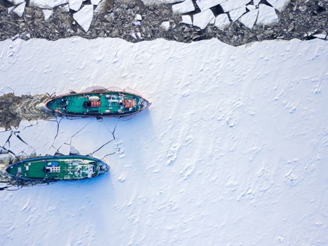 Ice breakers crush through the ice in an aerial shot