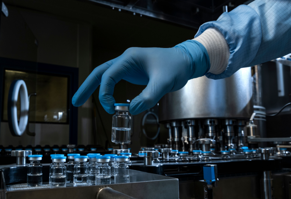 A gloved hand places a vial of medicine in a row