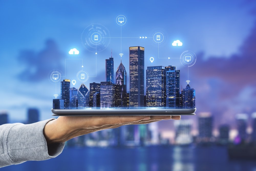 Smart city technologies concept with digital tablet and night megapolis city skyscrapers with digital cloud icons on human hand at blurry skyline background