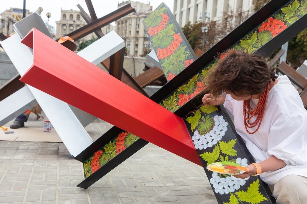 An artist draws patterns in Ukrainian national symbols on anti-tank hedgehogs in Kyiv, turning them into works of art.