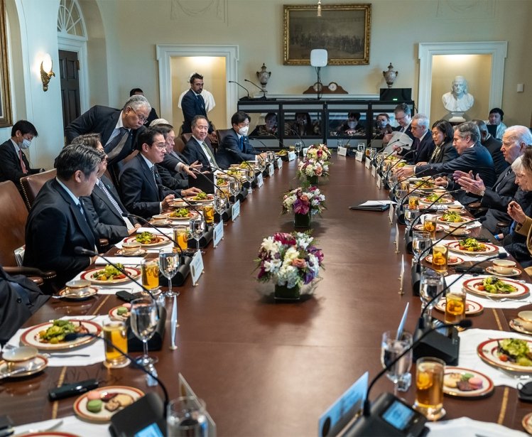 A group of delegates sits around an oval table.