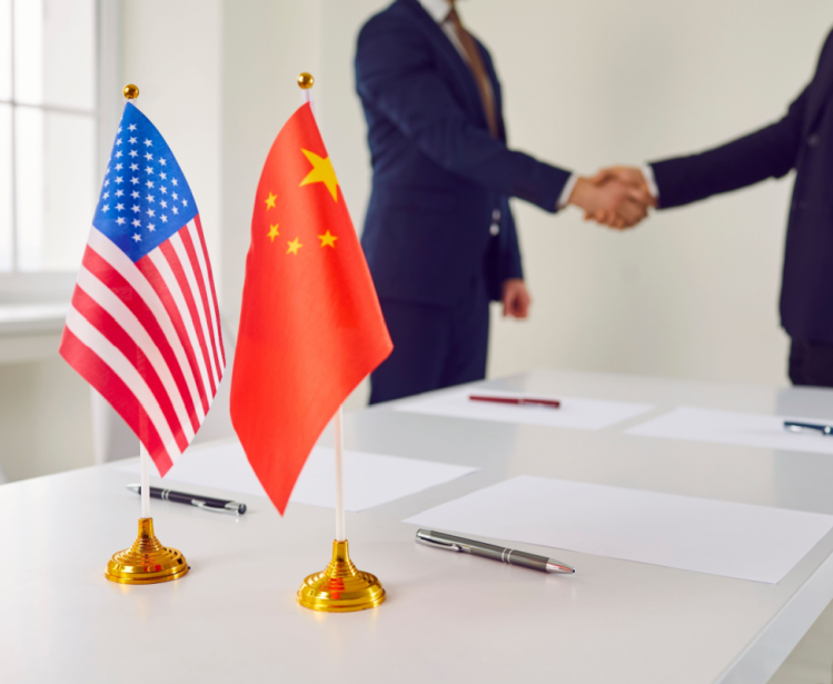 American and Chinese Flags with two people shaking hands in the background