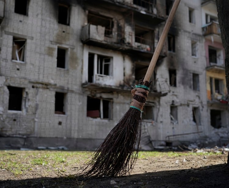 Broom in foreground, bombed building in background