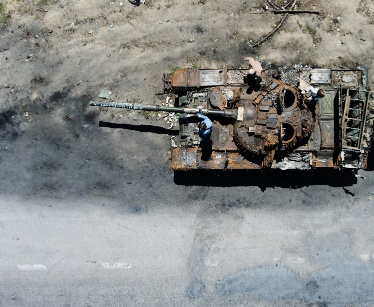 People climb on a destroyed russian tank after russian attack in Febrary