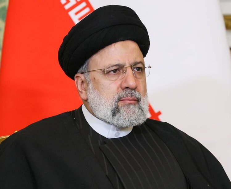 A picture of President Ebrahim Raisi seated in front of an Iranian flag.