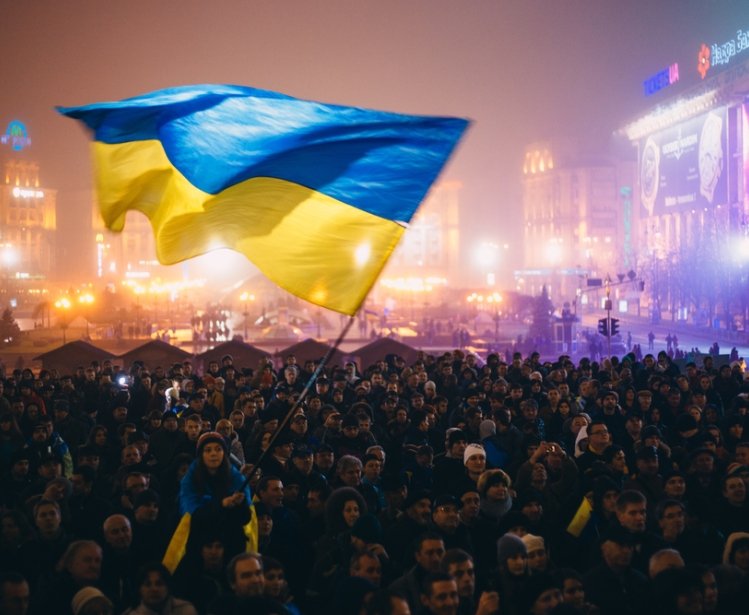 Meeting on the Independence square at night in Kiev. Girl holding a flag of Ukraine. During revolution to support the integration of Ukraine into the European Union.