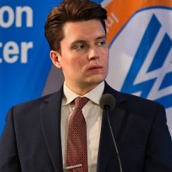 A photo of Lucas Myers speaking at a conference with the Wilson Center logo in the background.