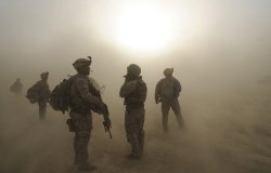 Soldiers watche as CH-47 helicopters circle above during a dust storm at Forward Operating Base Kushamond 