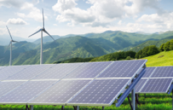 Solar panels and wind turbines against mountain landscape.