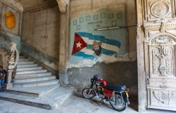 The image shows a painting of Fidel Castro on a worn-down wall in Old Havana