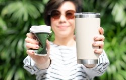 a woman holding one single-use cup and one reusable mug