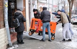 Group of men bringing an orange generator through a doorway