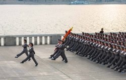 Squad of female teenagers in military uniforms rehearses for a parade