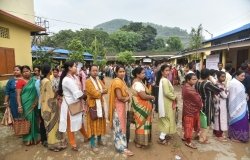 A group of people wait in line to cast their votes.